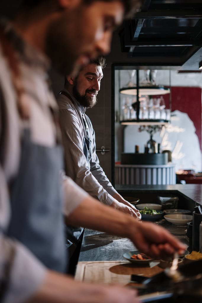 Two chefs preparing meals in a modern open kitchen setting.